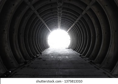 Exit from the empty white concrete tubing tunnel outside. Exit from bunker with light in the end. Inside empty concrete tubing tunnel. Abandoned tunnel with an apocalyptic feeling.