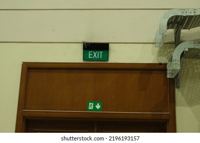 Exit Sign And Symbol Over Door In Hall