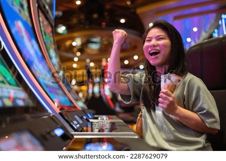 exited asia female woman slot machine gambling cheerful smile hand pressing bet button in casino club entertainment concept,exited asian woman hand play slot machine in casino hotel