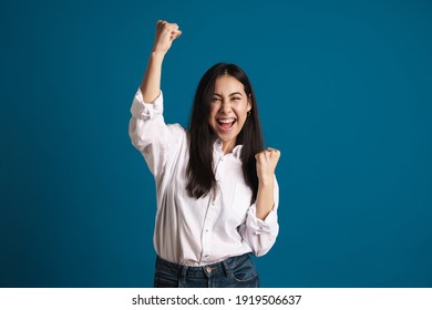 Exited Asian Girl Making Winner Gesture And Screaming Isolated Over Blue Background