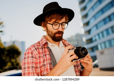Exited man with beard with interesting using retro film camera , making photos. Tourist mane walking in big modern city. 