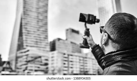 Exited man with beard with interesting using retro film camera , making photos. Tourist mane walking in big modern city.