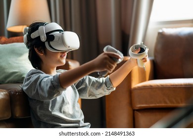 exiting asian child male boy enjoy metaverse gaming with wearable vr headset with control handle playing sport gaming online in living room at home,home technology young teen using vr technology - Powered by Shutterstock