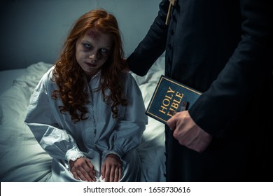 Exorcist Holding Bible And Hugging Demoniacal Girl In Bedroom