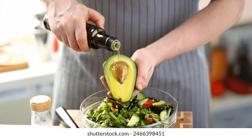 Exotic Avocado Seed Ingredient Poured Olive Oil. Male Hands Holding Half Tropical Fruit. Chef Cooking Healthy Vegetable Salad with Greens, Cucumber and Tomato. Dieting Culinary Food Horizontal Photo - Powered by Shutterstock