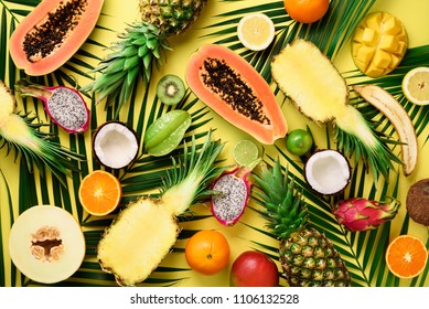 Exotic fruits and tropical palm leaves on pastel yellow background - papaya, mango, pineapple, banana, carambola, dragon fruit, kiwi, lemon, orange, melon, coconut, lime. Top view - Shutterstock ID 1106132528