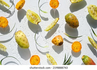 Exotic fruits, yellow and orange prickly pears, healthy cactus fruits on off white background with leaf. Flat lay, direct sunlight with shadows. Wet background with traces of water.