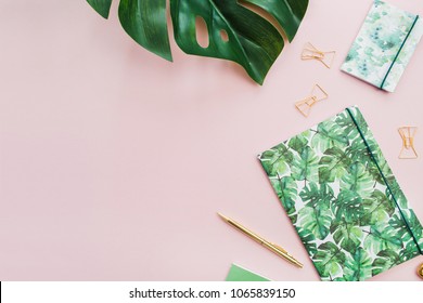 Exotic Tropical Monstera Palm Leaf And Home Office Stationery On Pale Pink Background. Flat Lay, Top View Minimal Workspace.