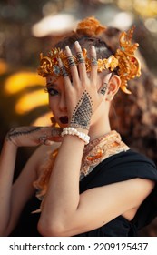 Exotic Woman In Her Bold Makeup While Wearing Golden Accessories On Her Head And Neck While In A Black Dress Inside The Forest