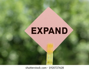 EXPAND - text on pink note paper on green background.