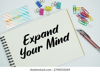 Expand Your Mind text message written on notepad with stationery flat lay on white background