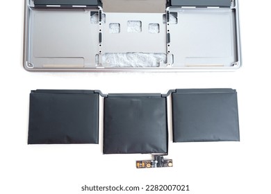 Expanded laptop battery is placed next to a laptop that has been taken apart. Importance of proper battery maintenance and the potential dangers of neglecting it.