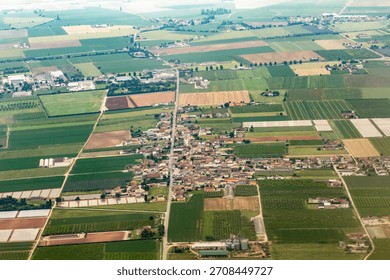 Expansive aerial perspective of agricultural fields surrounding a rural village, showcasing the beauty of nature.
