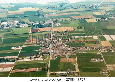 Expansive aerial perspective of agricultural fields surrounding a rural village, showcasing the beauty of nature.