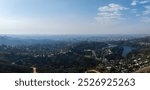 An expansive aerial view of Los Angeles features a reservoir surrounded by greenery and residential areas, with the city skyline in the distance.