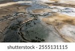 An expansive aerial view showcases a vast marshland, featuring winding streams and captivating cloud formations