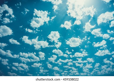 Expansive Background Of Scattered Clouds Over Blue Sky Highlighted By Bright High Noon Sun