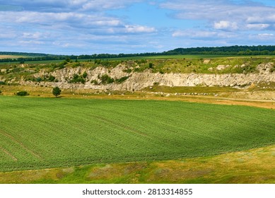 Expansive green fields and rocky cliffs under blue sky.