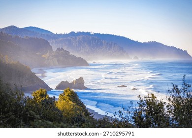An expansive, high-angle aerial view capturing the wide, sandy beach along Tillamook Bay, with the Pacific Ocean and surrounding coastal landscape under a clear, bright, sunny sky in Oregon