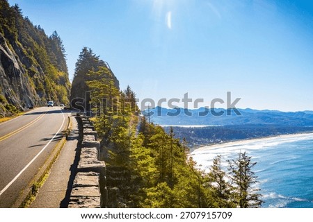 An expansive, high-angle aerial view capturing the wide, sandy beach along Tillamook Bay, with the Pacific Ocean and surrounding coastal landscape under a clear, bright, sunny sky in Oregon