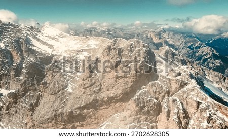 Expansive panoramic drone view over the endless snow-covered mountain ranges of the Italian Dolomites on a crisp and clear winter day, showcasing the majestic beauty of the Alps from a high altitude.