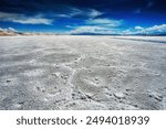 Expansive salt flats in Salinas Grandes, Jujuy, Argentina, showcasing breathtaking reflections under a clear blue sky, surrounded by mountains and a serene horizon.