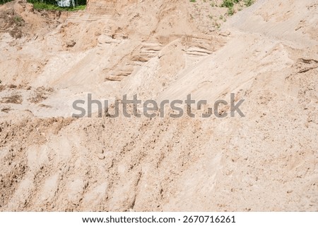 expansive sandy terrain with eroded layers and sparse vegetation under clear sky capturing natural geomorphology and texture variations in a dry landscape setting, solitary, open, granularity, rough