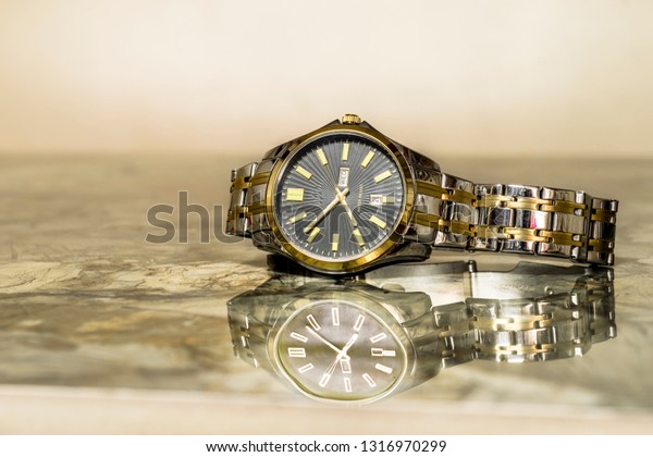 an expansive and\
stylish brand new silver and golden man\'s thin dial watch kept on a\
marble brownish floor 