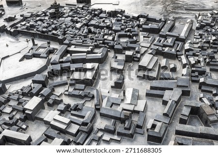 An expansive, top-down view of a dense, grey-scale urban model composed of thousands of rectangular concrete blocks. Ideal for architecture, planning, and city-design concepts.