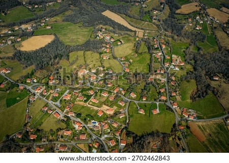 An expansive view of the charming Pays Basque region in France showcases lush green fields, small villages, and winding roads.