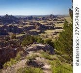 Expansive view of the dramatic geological formations and rolling hills of Badlands National Park under a clear blue sky
