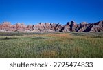 Expansive view of the dramatic geological formations of Badlands National Park, South Dakota, showcasing eroded buttes and a wide, grassy prairie