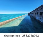 Expansive view of Fort Jefferson’s moat and turquoise waters under a cloudless sky, showcasing its architectural beauty.