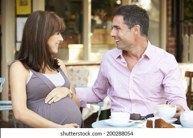 Expectant Couple Sitting Outside Cafe