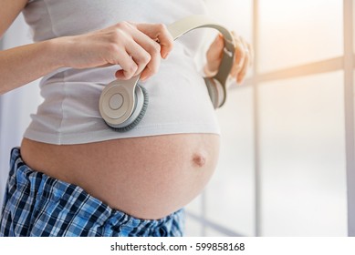Expectant mother enjoying music in bedroom