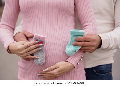 Expectant Parents Showcasing Baby Socks on Pregnant Belly. - Powered by Shutterstock