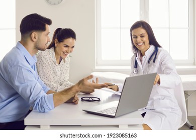 Expecting a baby. Smiling nurse showing scan picture to future parents. Happy couple, husband and his pregnant wife, looking at ultrasound image on computer screen sitting at table at doctor's office