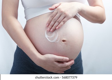 Expecting mother apply lotion on her belly, healthy skin pregnant woman.