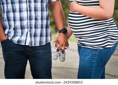 Expecting Native American couple holding hands with tiny baby moccasins (shoes) between them. Couple's maternity photo showcasing a pregnant belly.