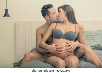 Expecting pregnant couple make cuddle in bed
