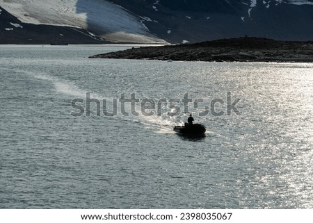 Expedition guide driving a rigid hull inflatable boat cruising in Magdalena Fjord in the Arctic ocean
