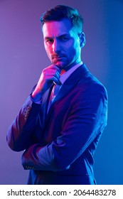 Expensive Lawyer Before A Court Hearing, The Chief Decision Maker For The Business. The Portrait Of A White Man Posing In Studio With Multicolored Neon Light On A Gray Background. High Quality Photo