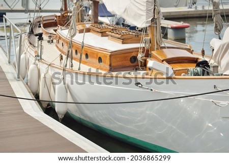 Expensive retro sailing boat (ketch) moored to a pier in a new yacht marina. Wooden teak deck, elegant details. Transportation, nautical vessel, vacations, tourism, cruising, regatta, recreation