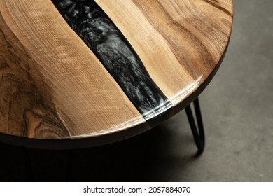 Expensive vintage furniture. The table is covered with epoxy resin and varnished. Luxury quality wood processing. Reflections of light in polished varnish.A black epoxy river in a round tree slab.