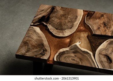 Expensive vintage furniture. The table is covered with epoxy resin and varnished. Luxury quality wood processing. Wooden table on a dark background. A gold epoxy river in a rectangular tree slab.