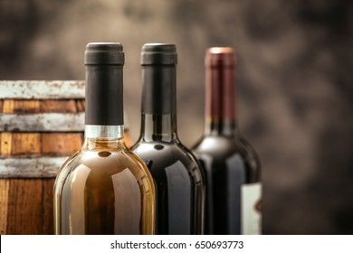 Expensive Wine Bottles Collection And Wooden Barrel In The Cellar, Wine Tasting And Production Concept