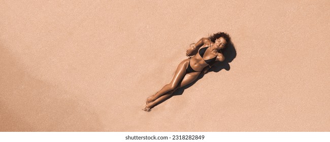Experience the beauty of the beach from above with this stunning aerial view of a woman in a bikini on a pink sand beach. Perfect for any travel, summer, or lifestyle campaign.