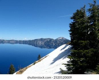 Experience the breathtaking beauty of Crater Lake, framed by a pristine blanket of snow. The vibrant blue waters contrast with the serene white surroundings, creating a captivating winter landscape. - Powered by Shutterstock