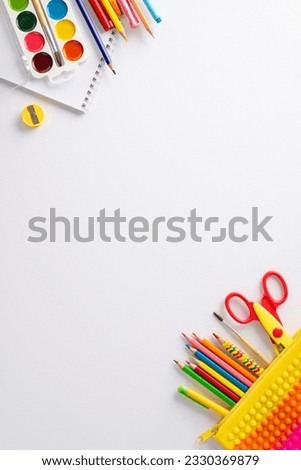 Experience the joy of studying art at school with this vertical top view composition: album, watercolour paints and vivid school supplies on white isolated background, perfect for text or adverts.