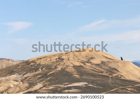 Experience the thrill of reaching the summit in Iceland! Breathtaking landscape with hikers scaling a golden mountain under a vast blue sky, inspiring travel and adventure.